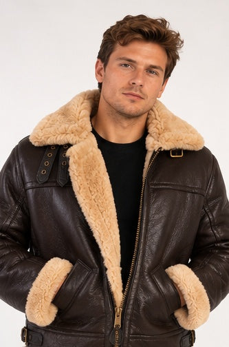A man wearing a dark brown leather aviator jacket with a thick beige shearling collar and matching shearling-lined pockets, photographed against a plain light background.